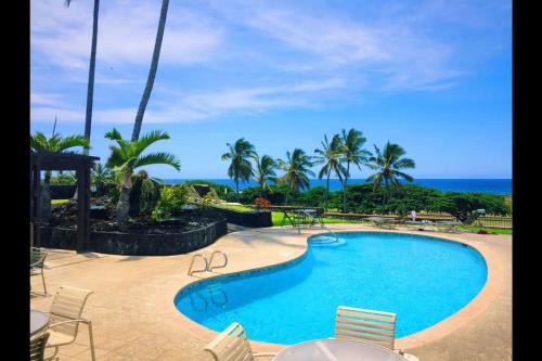 a swimming pool with chairs and the ocean in the background at Unit 05 Well Maintained Studio in Pahala