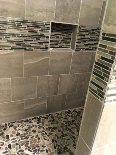 a bathroom with a shower with a tiled wall at Unit 25 Hula Hut Best Value in Pahala