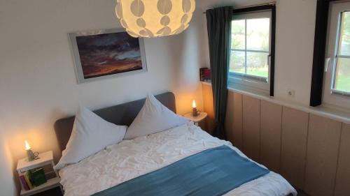 a bedroom with a bed and two windows and a chandelier at Landhaus-Sutje-Deichblick in Böhl