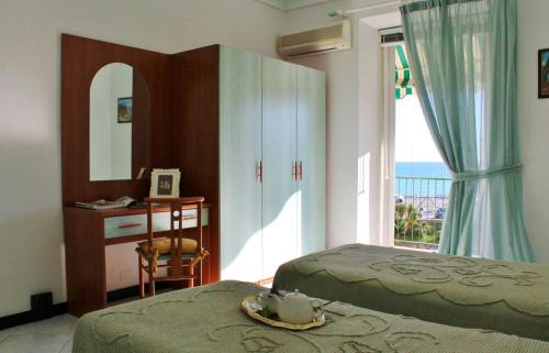 1 dormitorio con 2 camas, escritorio y ventana en Appartamenti Mare Azzurro by Holiday World, en Albisola Superiore