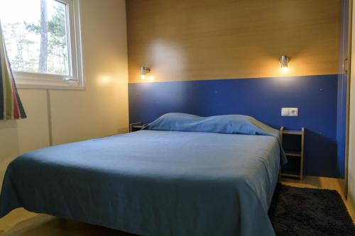 a blue bedroom with a bed with a blue wall at Parque de Campismo Orbitur Valverde in Luz