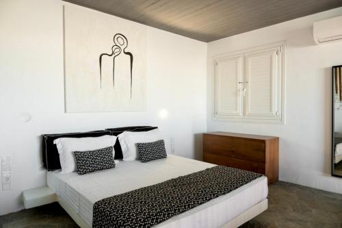 a white bedroom with a bed with black and white pillows at Mykonos Dot Art Homes in Ano Mera