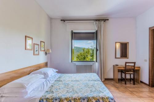 a bedroom with a bed and a window and a desk at B&B La Bufalona - Pool & Relax in Massa Marittima