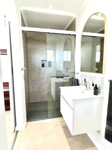 a white bathroom with a shower and a sink at Mountain View Studio Hermanus in Hermanus