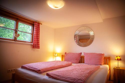 a bedroom with a bed with red and white sheets and a mirror at Landhaus Thanner in Ofterschwang