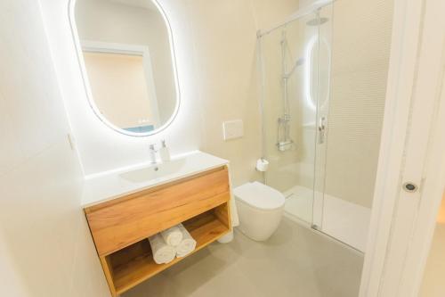a bathroom with a sink and a toilet and a mirror at Apartamentos Aires de Conil in Conil de la Frontera