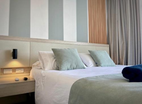 a hotel room with a bed with white sheets and blue pillows at Suite D’lujo: Jacuzzi privado BH in Santa Marta