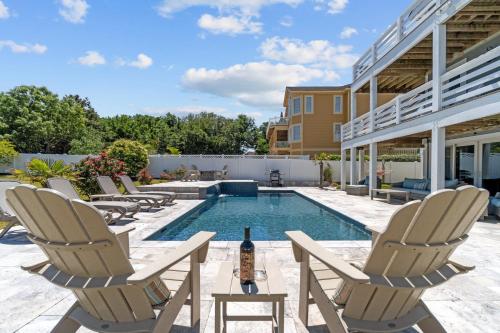 a patio with chairs and a pool with a bottle of wine at 4919 - The Leonardo in Kitty Hawk