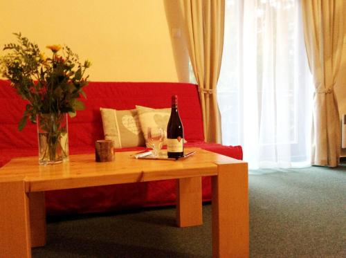 a red couch with a table with a bottle of wine at Penzion Bystrinka in Tale