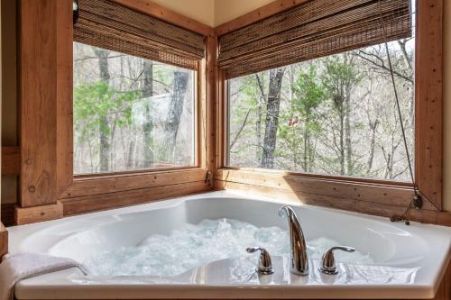 a bath tub in a bathroom with two windows at Shady Maples Lodge in Townsend