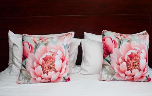 two pillows with pink flowers on a bed at Ocean View Villas B09 in Port Edward