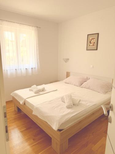 a large bed in a white room with a window at Apartments Niko Novalja in Novalja
