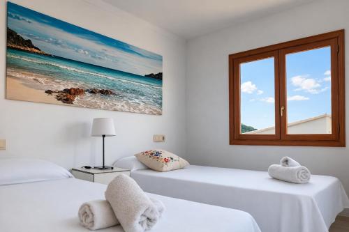 two beds in a white room with a window at Vila Mimosa in Colonia de Sant Pere