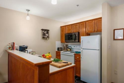a kitchen with a white refrigerator and wooden cabinets at Lux Stay USA Pool view Serenity Ski inout Hot Tub AS 339 in Snowshoe