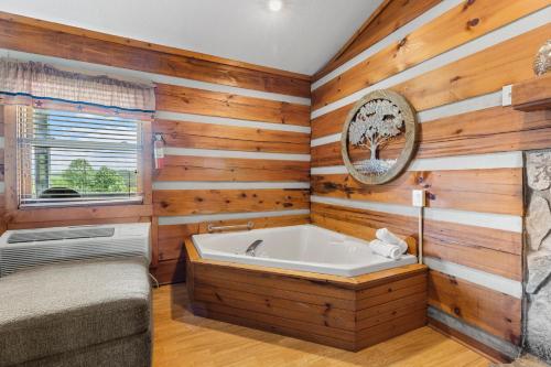 a bathroom with a tub and wooden walls at 2BR Cabin with Jacuzzi and Mountain Views - Cabin 5 in Fancy Gap