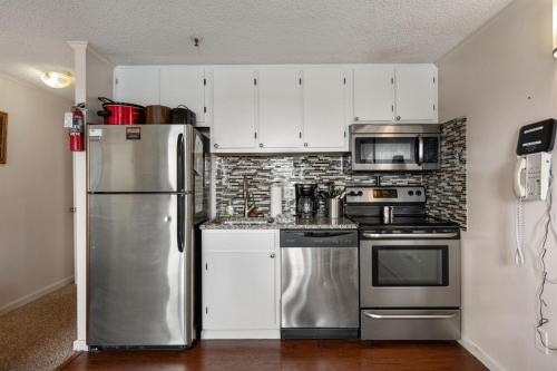 a kitchen with stainless steel appliances and white cabinets at Snowshoe Ski-InSki-Out Steps to Ballhooter Lift Mountain Lodge Condo in Snowshoe