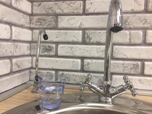 a glass of water sitting next to a sink at Horoshy Hostel in Chelyabinsk