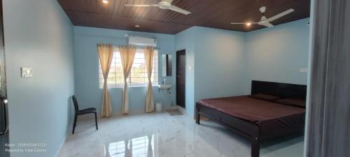 a bedroom with a bed and a chair and a window at Srinivasa Hotel in Narasingāpuram