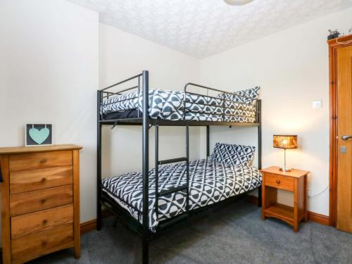 a bedroom with two bunk beds and a dresser at 36 Cae Rhos in Holyhead