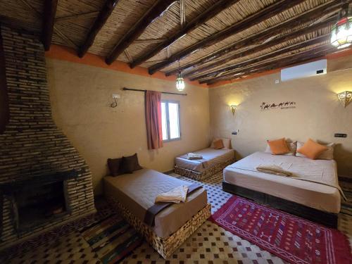 a bedroom with two beds and a fireplace at Riad Berber in Merzouga