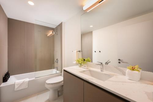 a bathroom with a sink and a toilet and a tub at Sense28 Edgewater, an AvantStay Hotel in Miami