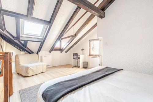 a bedroom with a large bed and a chair at Duplex Centre historique in Strasbourg