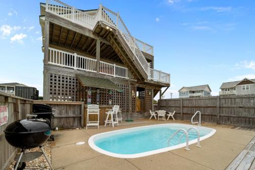 a backyard with a swimming pool and a house with a staircase at 4744 - Sandy Beaches in Kitty Hawk Beach