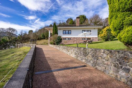 a white house with a stone retaining wall and a sidewalk at Vivienda Vacacional La Seronda in Ribadesella