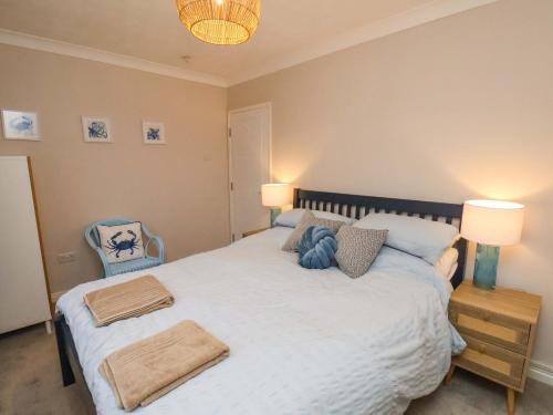 a bedroom with a large bed with two lamps and a chair at Seashells at Runswick Lodge in Saltburn-by-the-Sea