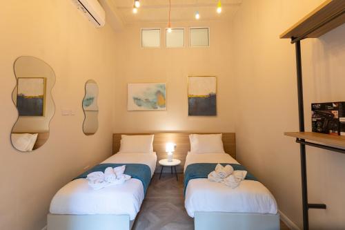 two beds in a room with mirrors on the walls at Pawlina Boutique Residence in St. Paul's Bay