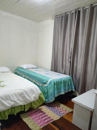 a small room with two beds and a window at Um lar acolhedor in Pato Branco