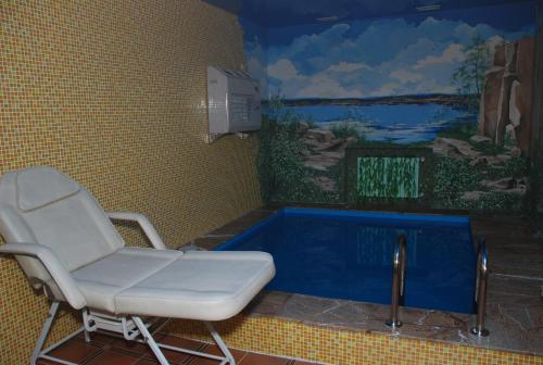 a bath room with a chair and a tub at Status Hotel in Poltava