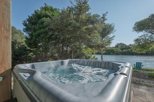 a hot tub on a porch with a view of a lake at 1064 - Sunset Cottage in Corolla