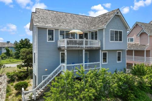 a blue house with a balcony and an umbrella at 5592 - Windjammer in Nags Head