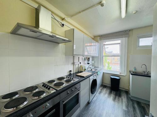 a kitchen with a stove and a washing machine at Stay on Brick Lane in London