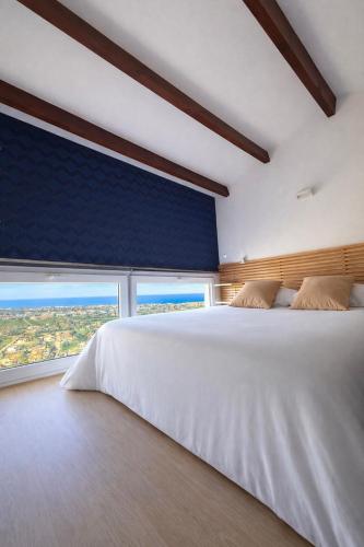a bedroom with a large white bed and two windows at Mediterranean View Apartment in Denia