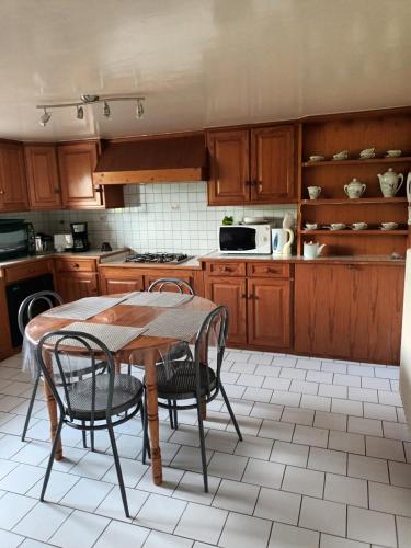 eine Küche mit Holzschränken, einem Tisch und Stühlen in der Unterkunft Ty Kerlen in Quimperlé