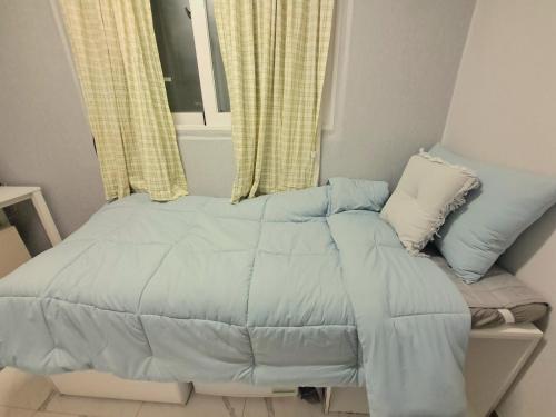 a bed with a blue comforter and a window at Dodahm guesthouse stay in Incheon