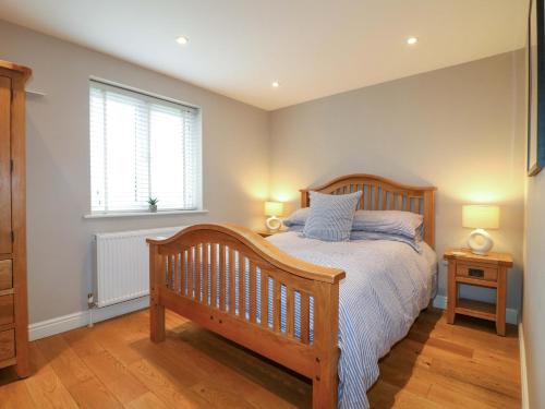 a bedroom with a wooden bed and a window at Farm View House in Melton Mowbray
