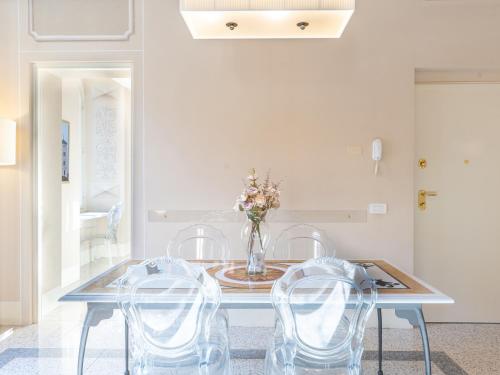 a dining room with a table with chairs and a vase with flowers at Noble Floor - Panoramic Luxury Apartment in Lucca