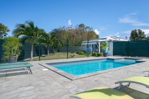 a swimming pool with two chairs and a fence at Villa Sibaloma in Saint-François