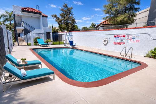 a swimming pool with two chairs next to a building at Express Inn & Suites Ontario Airport in Ontario