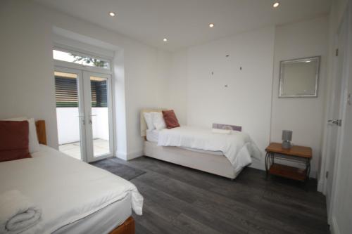 a white room with two beds and a window at Osterley Place - Apt A in Hounslow