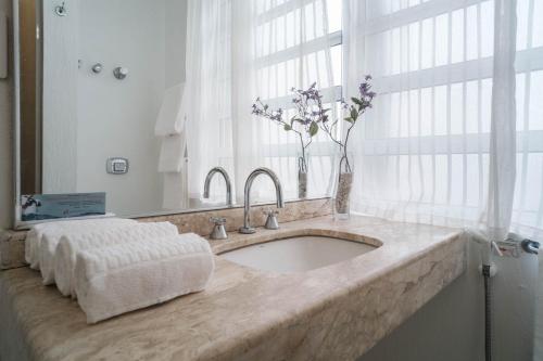 a bathroom sink with a vase of flowers on it at Hotel Normandie - by Easy Hotéis in São Paulo