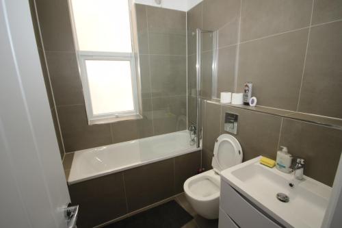 a bathroom with a toilet and a tub and a sink at Osterley Place - Apt F in Hounslow