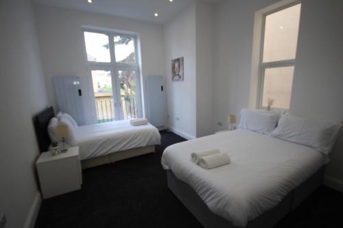 a white room with two beds and a window at Osterley Place - Apt F in Hounslow