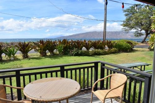 two chairs and a table on a balcony overlooking the water at Nona Lani Cottages in Kihei