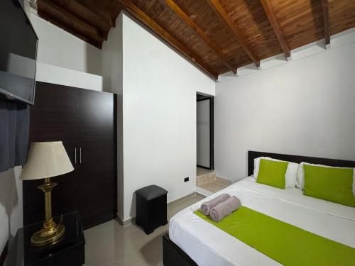 a bedroom with a bed with green pillows and a lamp at Balcón Paisa SAS in Medellín