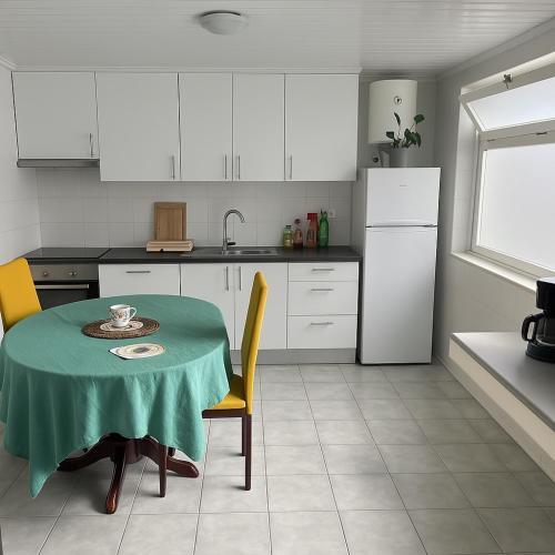 a kitchen with a table with a green table cloth on it at Espaço perto aeroporto in Ponta Delgada