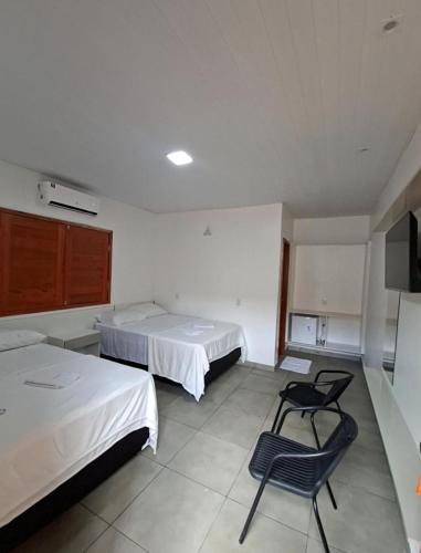 a room with two beds and a chair in it at Cachoeira e Pousada dos Pássaros in Presidente Figueiredo